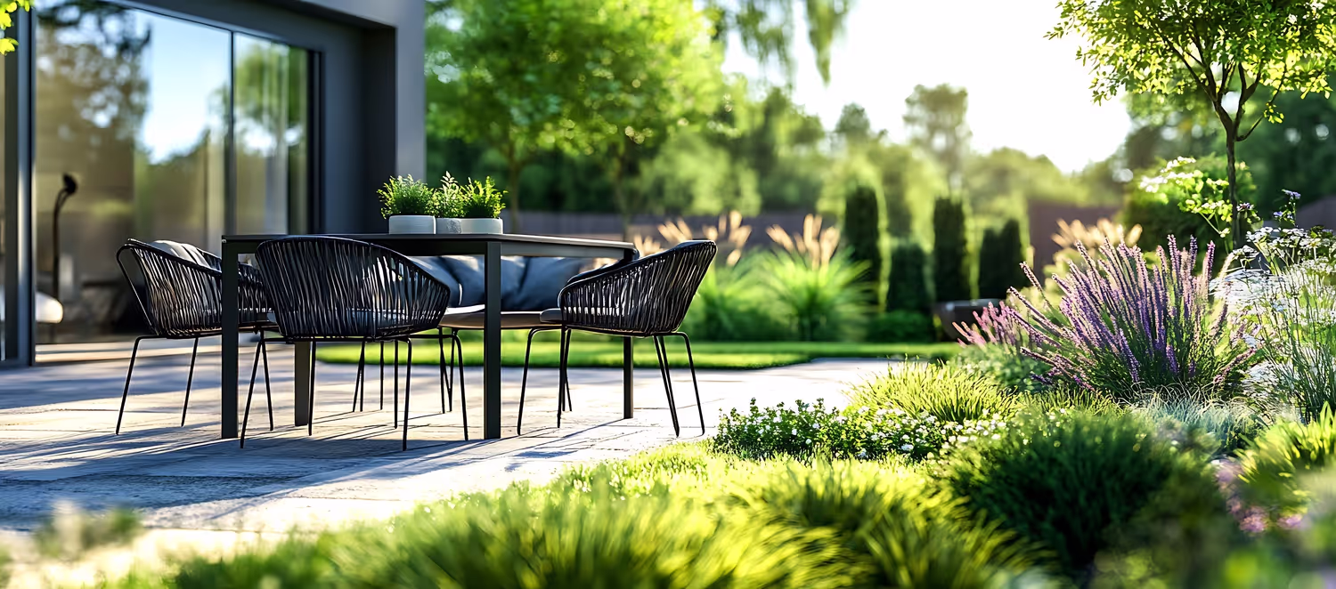Moderne Terrassenmöbel eingebettet in einen üppigen grünen Garten mit leuchtend violetten Blumen